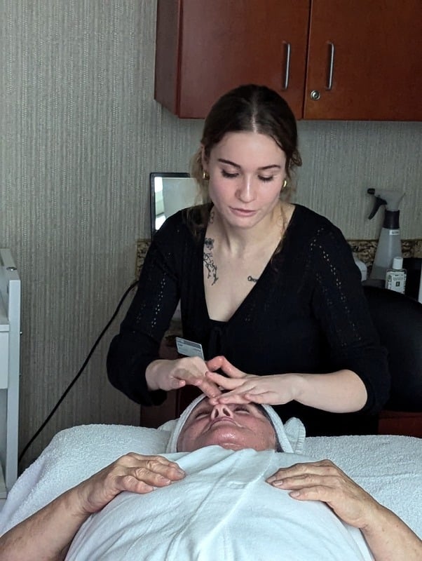 Kendal, an esthetician, performing a treatment on a client in a calm spa treatment room.
